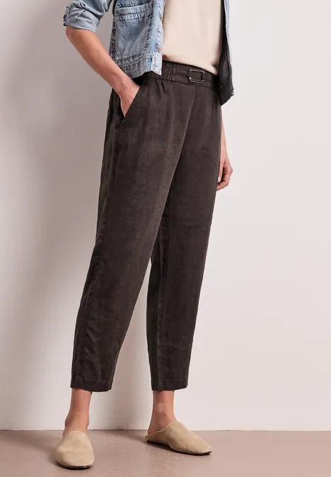 Dunkelgraue Cordhose mit Gummibund und -bündchen, kombiniert mit beigen Hausschuhen.